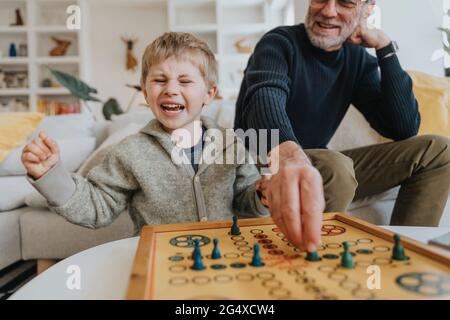 Cheerful son playing ludo game with father at home Stock Photo