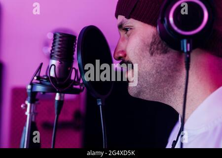 Male singer looking away while singing at studio Stock Photo