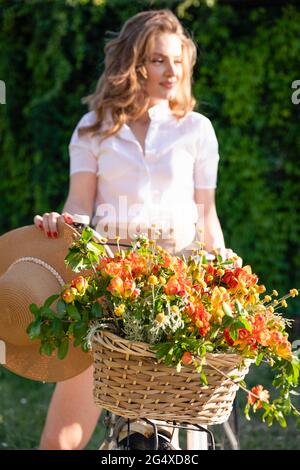Freesia flowers in basket with young woman on bicycle Stock Photo