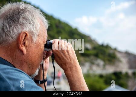 Senior man looking through binoculars Stock Photo