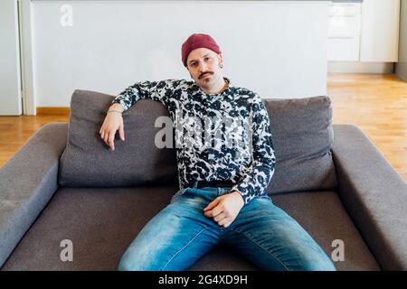 Young man sitting on sofa at home Stock Photo