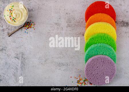 White icing in bowl with round sponge cake. Stock Photo