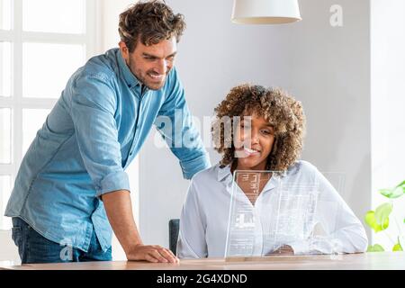 Businessman standing by colleague using futuristic digital tablet in office Stock Photo