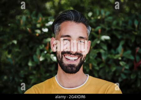 Bearded man smiling in front of plants Stock Photo