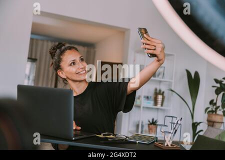 Businesswoman taking selfie through smart phone at office Stock Photo