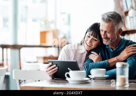 Business couple smiling while using digital tablet at cafe Stock Photo