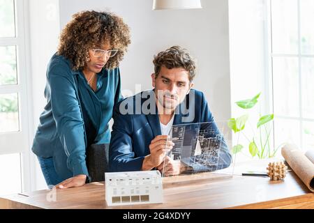 Male and female architects working on futuristic digital tablet at office Stock Photo