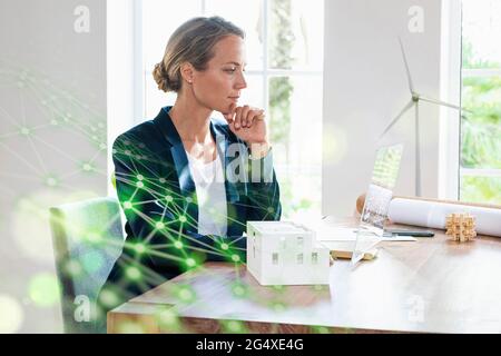 Businesswoman with hand on chin using futuristic digital tablet at office Stock Photo