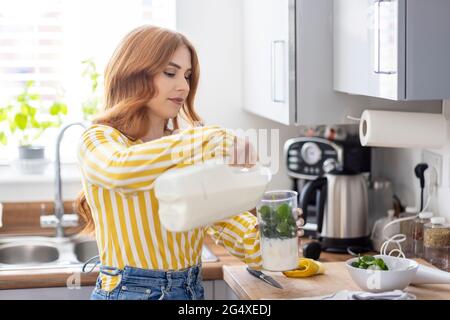 Woman pouring milk in blender while preparing fruit juice at home Stock  Photo - Alamy