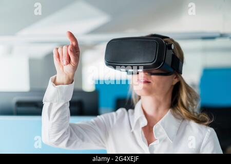 Businesswoman gesturing while using virtual reality headset in office Stock Photo