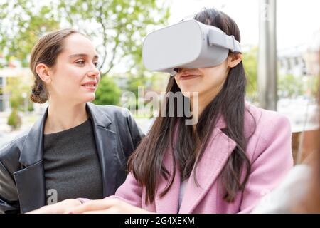 Businesswoman looking at colleague using virtual reality headset Stock Photo