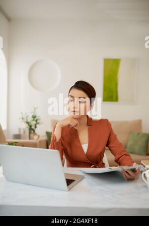 Portrait of pretty cheerful accountant looking away sitting at desk in modern office Stock Photo