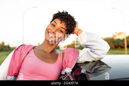 Young woman with head in hand standing near car Stock Photo