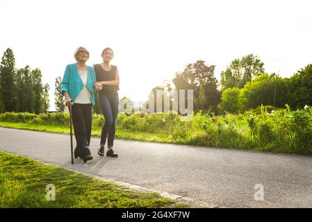 Mid-adult woman supporting senior woman while walking in park Stock Photo