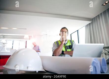 Thoughtful architect looking away while sitting in office Stock Photo
