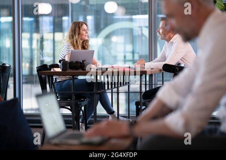 Male and female professionals discussing at table in office Stock Photo