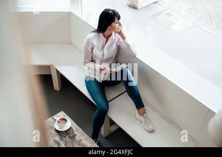 Thoughtful female owner with digital tablet looking away at cafe Stock Photo