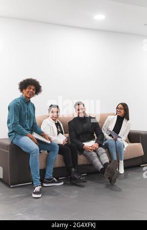 Cheerful male and female professional sitting on sofa at office Stock Photo