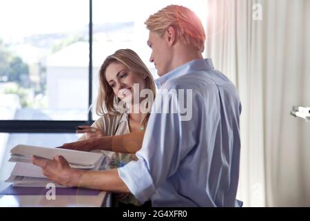 Man discussing over documents with female colleague at office Stock Photo