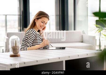 Smiling female entrepreneur using graphics tablet at table in office Stock Photo