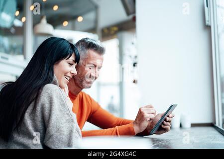Smiling mature couple using smart phone at cafe Stock Photo