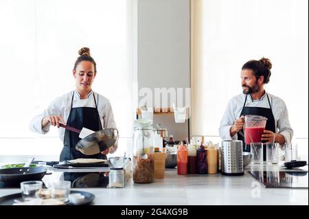 Professional chefs talking while cooking in kitchen at modern restaurant Stock Photo