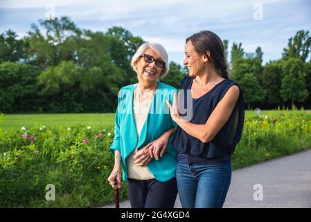 Caring mid-adult woman with senior woman walking in park Stock Photo