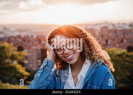 Smiling woman with hand in hair during sunset Stock Photo