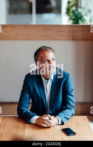 Thoughtful businessman looking away while sitting at office Stock Photo