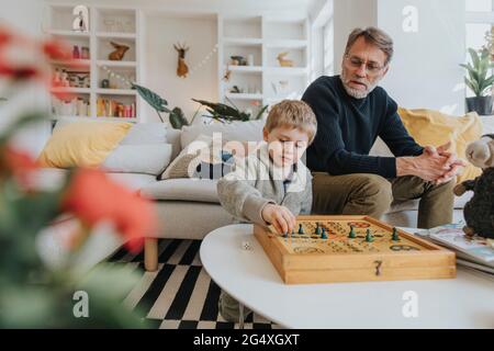 Father and son playing ludo in living room at home Stock Photo