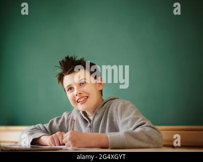 Smiling boy looking away while studying at home Stock Photo