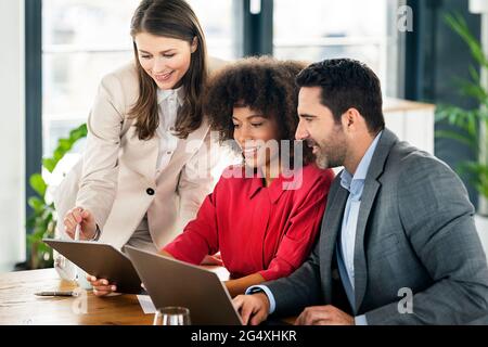 Smiling male and female professionals working on graphics tablets in office Stock Photo