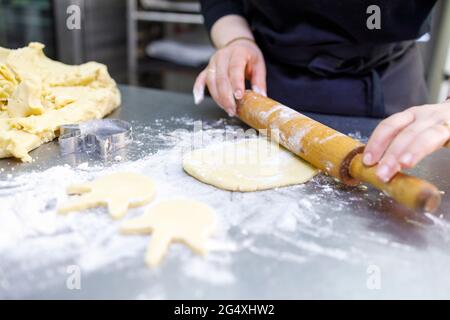 Female baker rolling dough in bakery Stock Photo