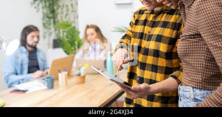 Businessman discussing over digital tablet with female colleague in creative office Stock Photo