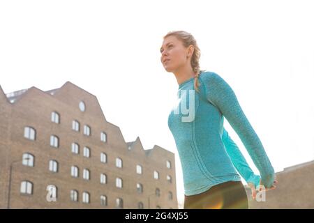 Young woman with hands behind back stretching on sunny day Stock Photo