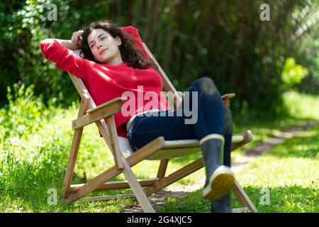 Young woman looking away while relaxing on chair in garden Stock Photo