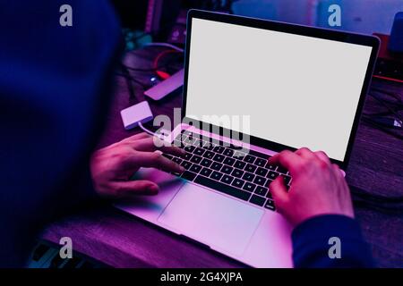 Male computer hacker stealing data on laptop at home Stock Photo
