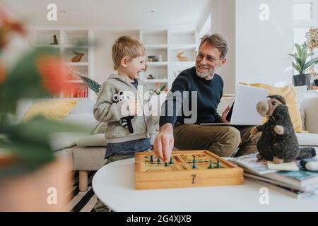 Happy father playing ludo game with son at home Stock Photo