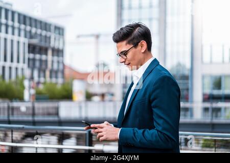Male entrepreneur using smart phone by railing Stock Photo