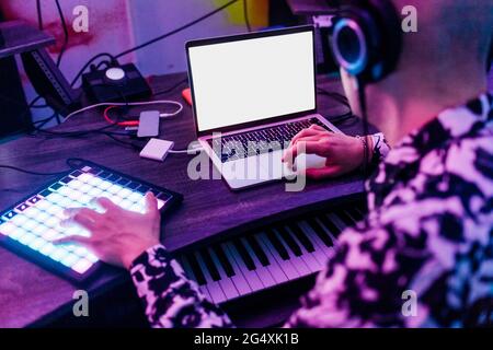 Male composer wearing headphones using laptop and digital tablet in studio Stock Photo