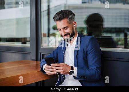 Male entrepreneur using mobile phone while sitting at cafeteria Stock Photo