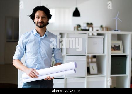 Young male entrepreneur holding document while standing in office Stock Photo