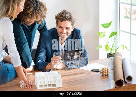 Male architect with futuristic device screen working by colleagues in office Stock Photo