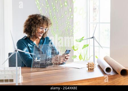 Businesswoman using mobile phone by futuristic device screen and network connection in office Stock Photo