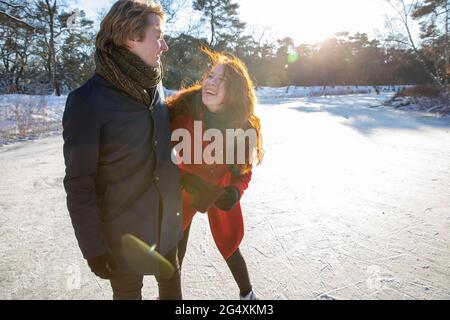 Happy couple standing on frozen lake during sunny day Stock Photo