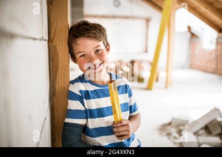 Smiling boy holding tape measure during house renovation Stock Photo