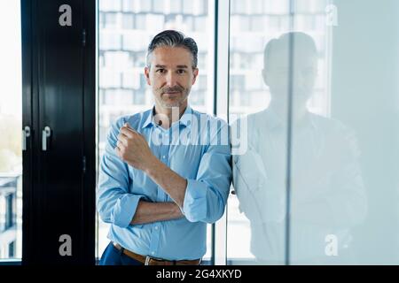 Male entrepreneur leaning on white board while standing in office Stock Photo