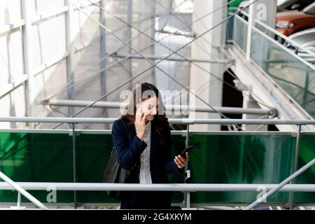Female professional talking on smart phone while standing near railing Stock Photo