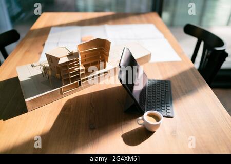 Laptop with coffee cup and architectural model on table at office Stock Photo
