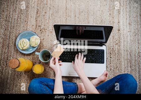 Young woman using laptop while doing online shopping with credit card at home Stock Photo